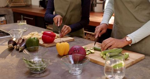 Diverse friends cooking together chopping vegetables in modern kitchen