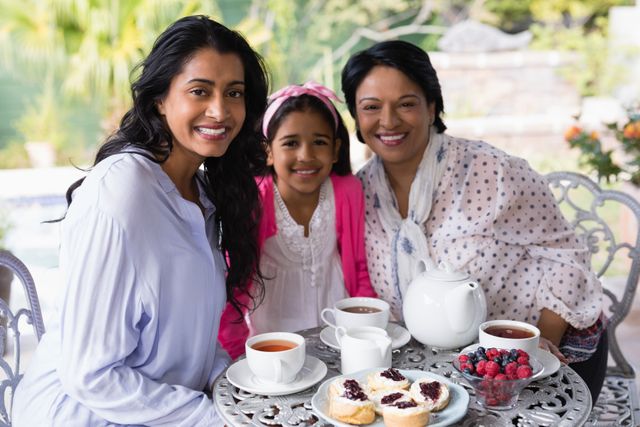 Three generations of women sitting together at a breakfast table, enjoying tea and pastries. Ideal for concepts related to family bonding, morning routines, and intergenerational relationships. Perfect for use in advertisements, family-oriented content, and lifestyle blogs.