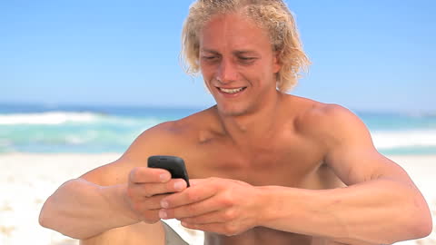 Blonde Man Enjoying Sunny Beach with Smartphone