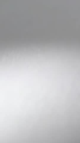 Vertical video shifting light revealing subtle gray wall texture and soft gradient motion