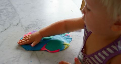 Child engaging in creative play with colorful clay at home