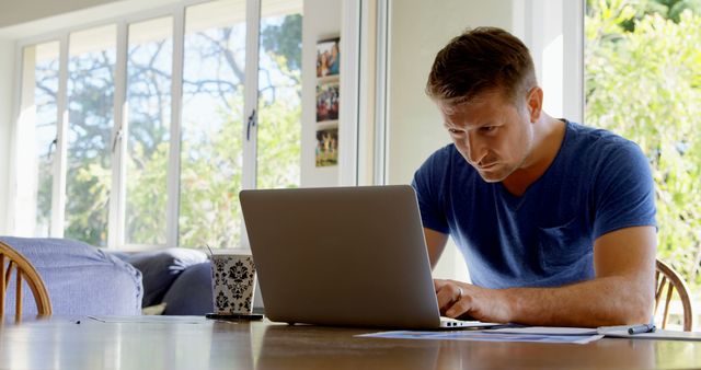 Focused Man Working on Laptop at Home Near Large Windows - Download Free Stock Images Pikwizard.com