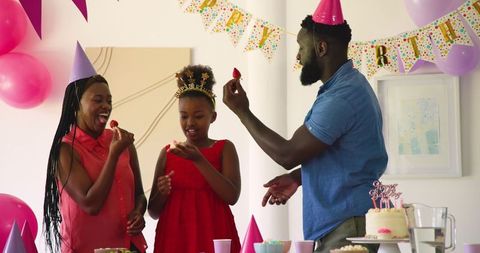 Family Celebrating Child's Birthday with Cake and Party Hats