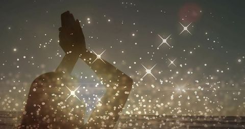Silhouette woman raising hands in prayer at sunset with starry bokeh double exposure