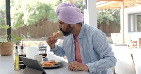 Man in Turban Using Tablet While Eating Breakfast at Home