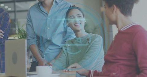 Smiling woman leading team brainstorming around laptop in open workspace