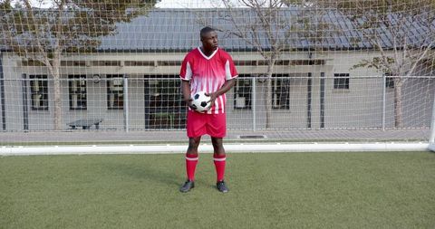 Goalkeeper Holding Soccer Ball Standing Before Goal Net