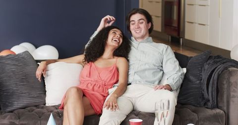 Happy Couple Enjoying After-Party Relaxation on Living Room Sofa
