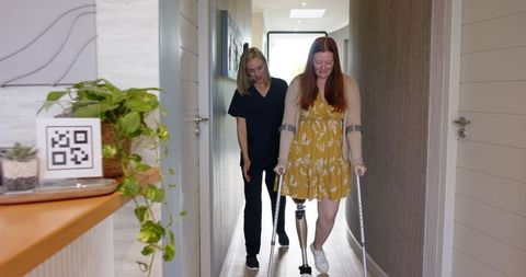 Therapist Assisting Woman with Prosthetic Leg Using Crutches