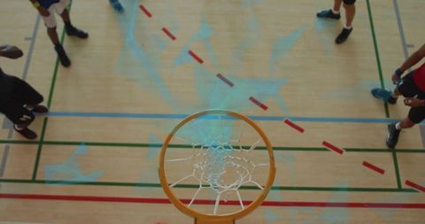 Overhead basketball hoop framing players on indoor court during team practice
