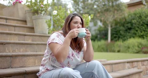 Plus size woman enjoying outdoor coffee break sitting steps