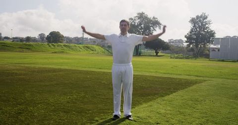 Male athlete standing on sunny cricket field ready to play