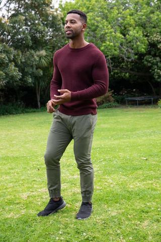 Man in Casual Wear Walking on a Sunny Lawn Amidst Lush Greenery