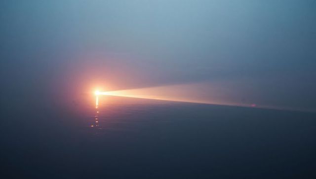 Luminous Beam Over Calm Sea at Dawn