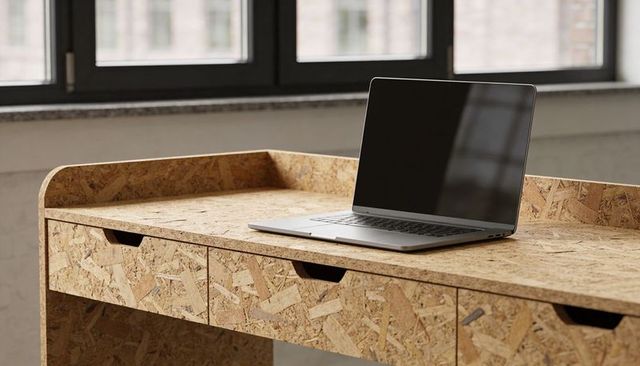 Minimalist laptop on osb desk in industrial workspace with paned windows and natural light