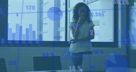 Businesswoman analyzing data overlaid with graphs in conference room