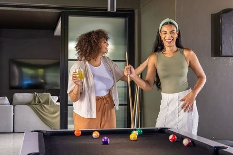Laughing african american friends playing pool in stylish home lounge