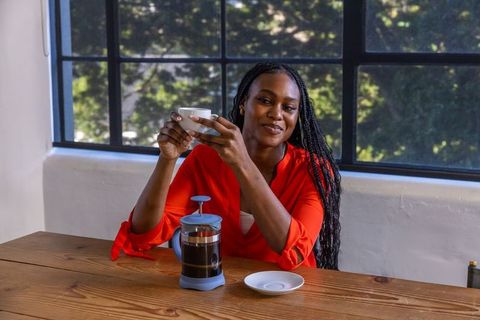 Woman Enjoying Hot Beverage at Rustic Kitchen Table with French Press