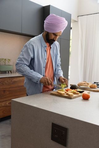 Middle-aged indian man preparing healthy meal in modern kitchen
