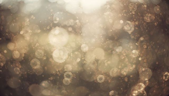 Shimmering golden bokeh with sunlit dust particles creating warm ethereal glow background