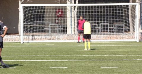 Soccer Player Kicking Ball Towards Goal in Practice Match