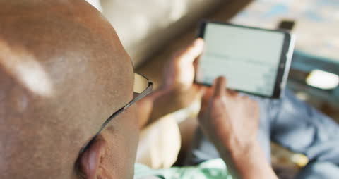 Elderly Man Relaxing at Home Using Tablet Technology