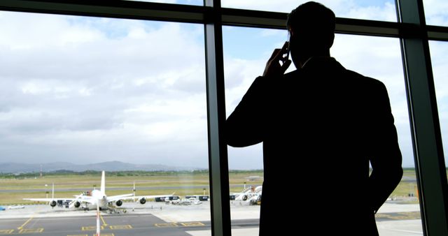 Businessman Talking on Phone at Airport Terminal Window - Download Free Stock Images Pikwizard.com