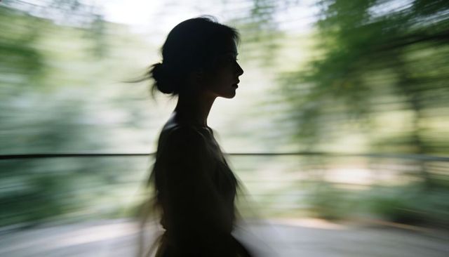 Silhouetted woman standing on balcony with flowing dress and radial motion blur
