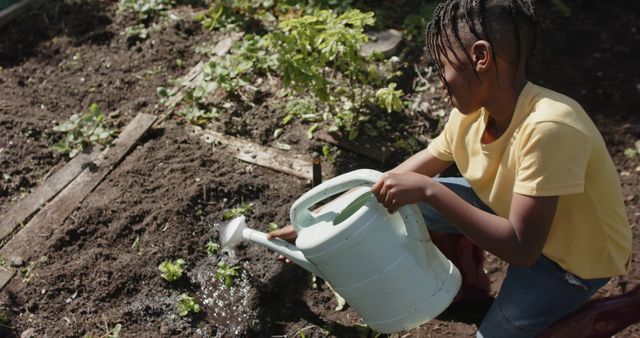 Happy african american boy watering plants in sunny garden. Organic food, gardening and healthy life style, unaltered.