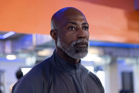 Mature african american man standing in gym wearing zip-up jacket, focused portrait