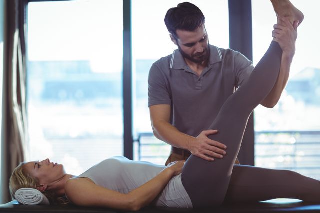 Physiotherapist performing leg stretch on patient in clinic. Useful for illustrating physical therapy, rehabilitation, healthcare services, and wellness programs. Ideal for medical websites, health blogs, and educational materials on physiotherapy.