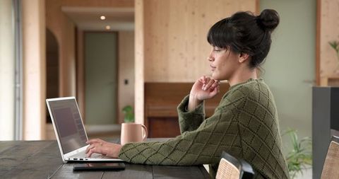 Focused Woman Working at Home on Laptop in Modern Minimalist Space