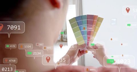 Designer holding paint swatch fan and comparing colors with augmented reality overlays