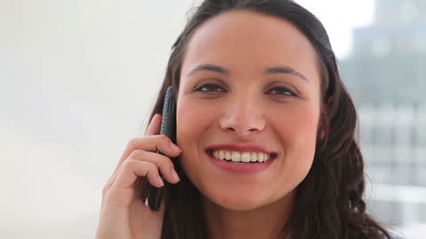 Woman Smiling Talking on Phone in Bright Office Environment