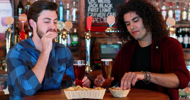 Two friends enjoying drinks and snacks in a bar - Download Free Stock Images Pikwizard.com