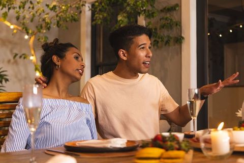 Couple leaning in on candlelit terrace sharing conversation and warm evening laughter