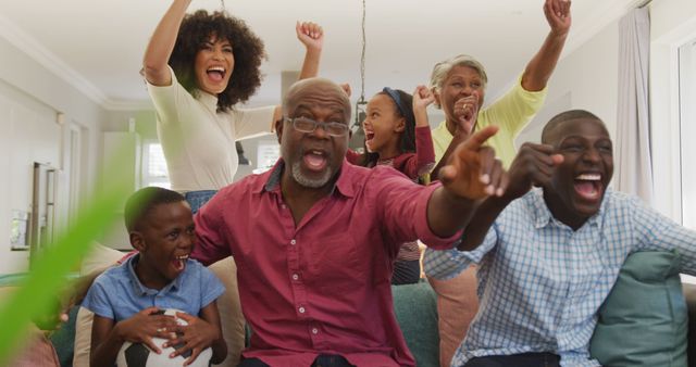 Multi-generational family cheering together indoors. Grandparents, parents, and children expressing joy. Ideal for illustrating themes of family bonding, celebrations, and joyful moments.