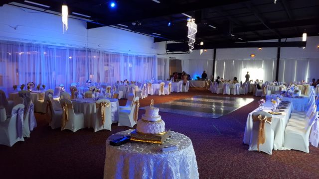 This beautifully decorated wedding reception ballroom features an elegant cake centerpiece under a blue-lit ambiance. Perfect for websites and materials related to wedding planning, events, party venues, catering services, and luxury gatherings.