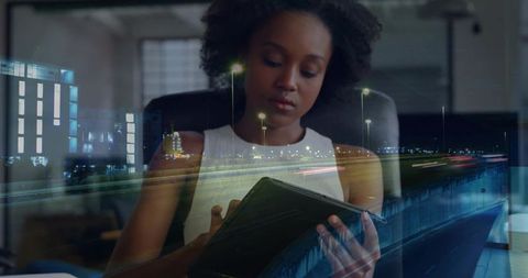 Young professional working on tablet with night highway light trails overlay