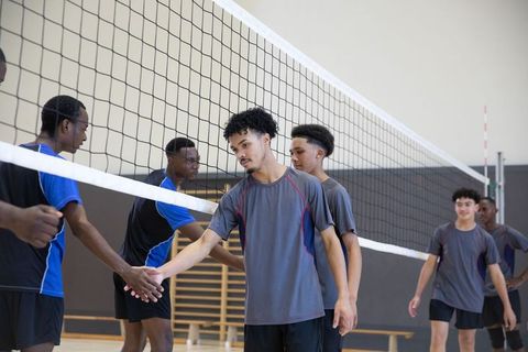 African american high school volleyball players showing sportsmanship shaking hands across net
