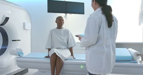 African american woman sitting on ct scanner table receiving care from technologist