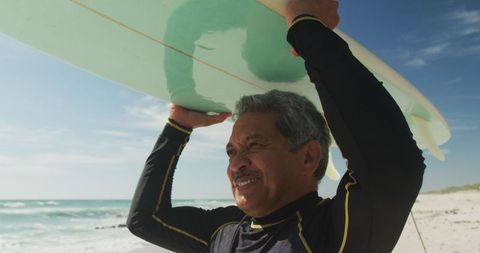 Senior Hispanic Man Holding Surfboard on Beach Under Blue Sky - Download Free Stock Images Pikwizard.com