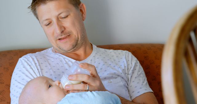 Father Feeding Infant with Bottle While Sitting on Couch - Download Free Stock Images Pikwizard.com