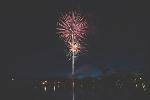 Vibrant fireworks lighting up night sky over tranquil lake