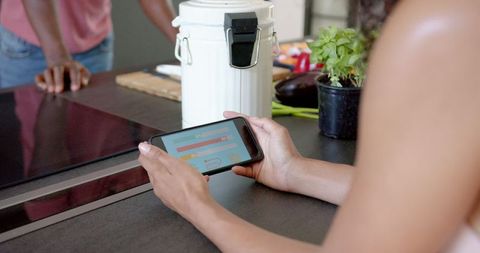 Person checking health app on smartphone at kitchen counter