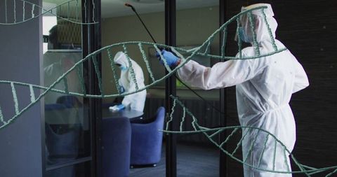 Hazmat technicians disinfecting office conference glass wearing ppe and using spray wand