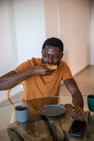 Man enjoying sandwich at glass dining table in modern interior