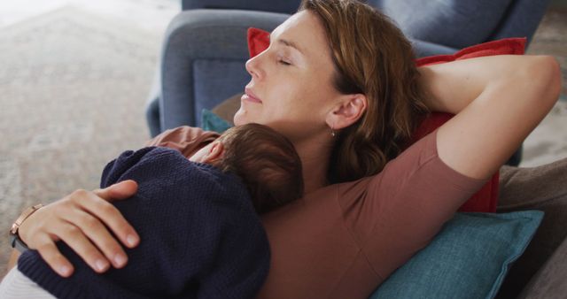 Mother resting on couch with baby asleep in her arms, showcasing a peaceful and intimate moment of motherhood and bonding. Perfect for parenting blogs, family and lifestyle articles, maternal health promotions, and advertisements promoting comfort and home life.