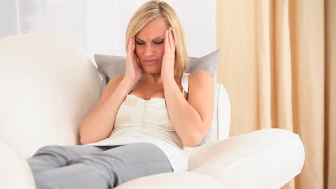 Woman Experiencing Headache on Sofa at Home