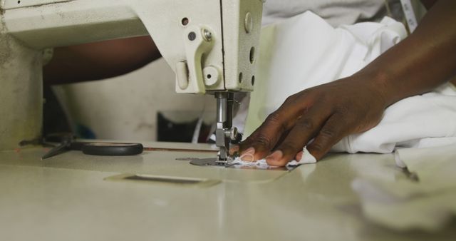 Hand of african american male tailor using sewing machine in workshop. Tailor, small business, work, labor and workshop, unaltered.